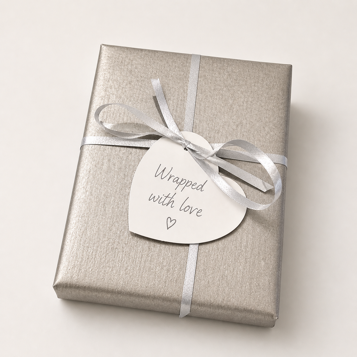 Silver kraft gift wrap with ribbon, logo seal, heart tag, and kraft box ready for gifting